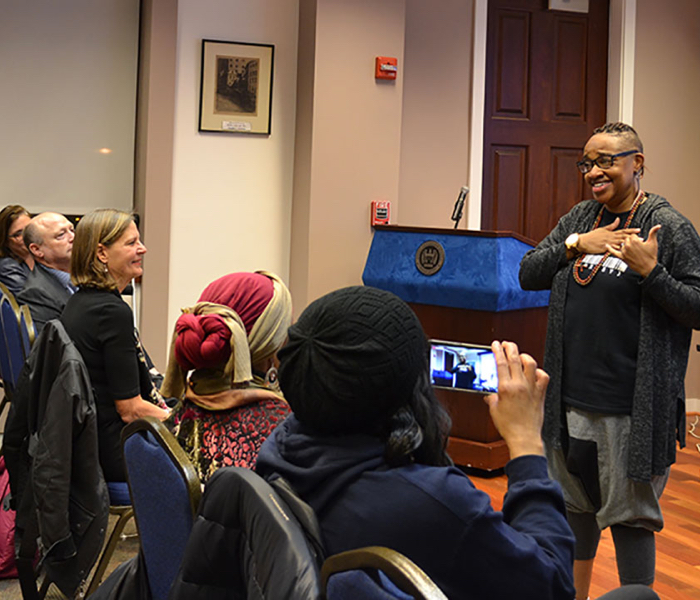 A person speaks to a class with a podium in the background.