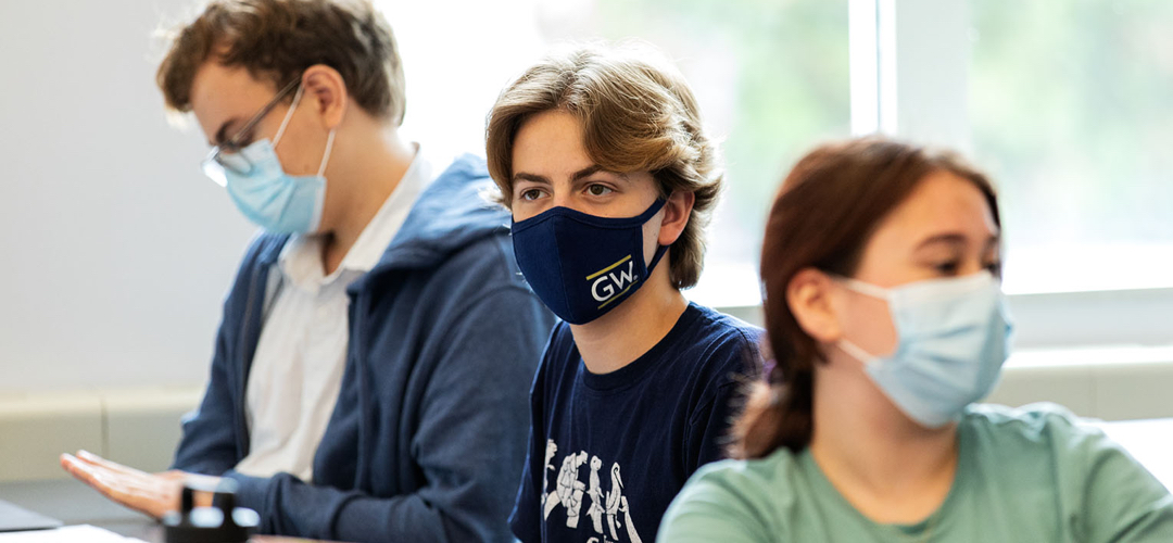Three students wearing face masks in a classroom