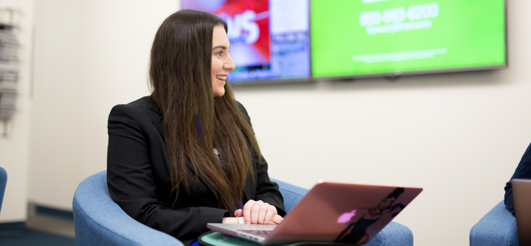 A student sits in a chair with a laptop computer.
