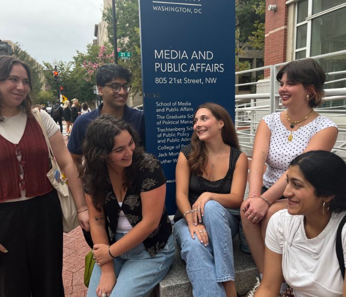 Students sitting outside of the MPA sign