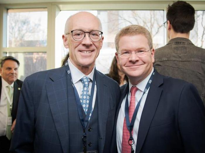 Two men in suits and ties smiling together for the camera