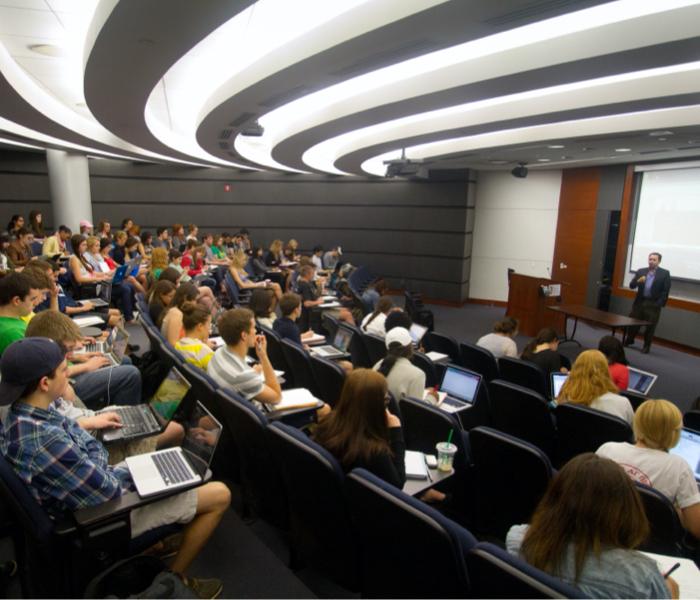 A professor speaks to a large classroom of students
