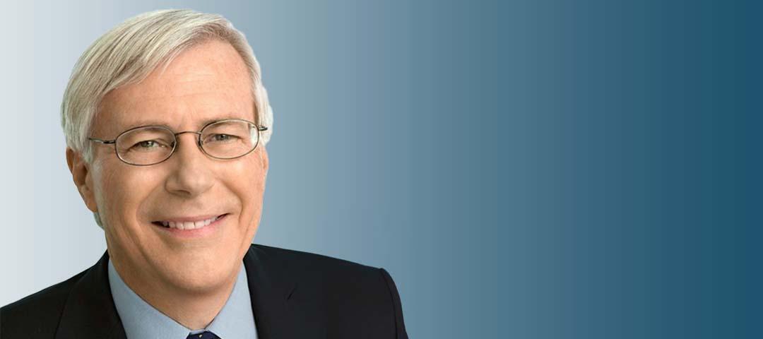 Decker Anstrom in a black suit and tie against a blue background
