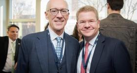 Two men in suits and ties smiling together for the camera